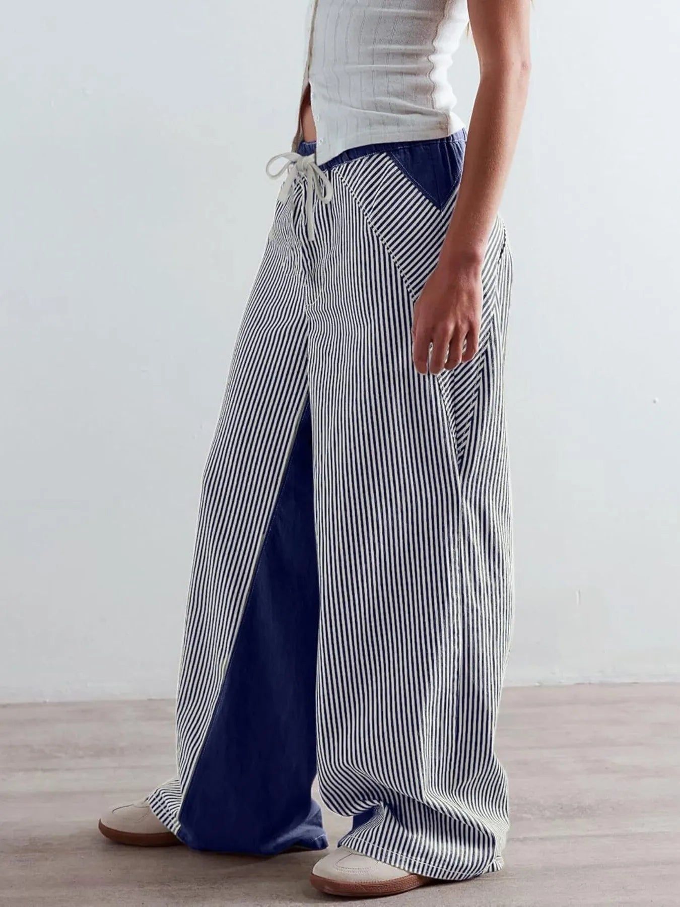 Person wearing blue and white striped wide-leg pants on a plain background