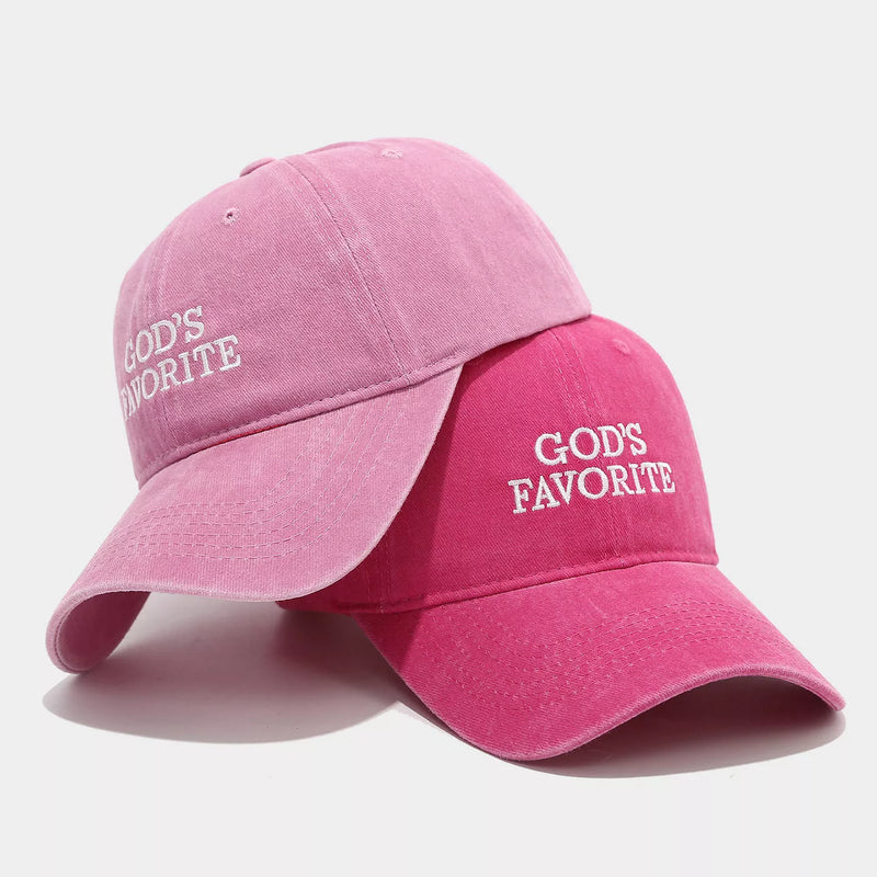 Two pink baseball caps with 'GOD'S FAVORITE' text on a light gray background