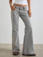 Person wearing light gray flared jeans on a plain background