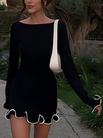 Woman wearing a black dress with a white trim in an outdoor setting