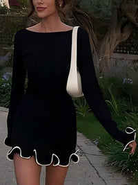 Woman wearing a black dress with a white trim in an outdoor setting