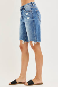 Denim shorts worn by a person on a plain background