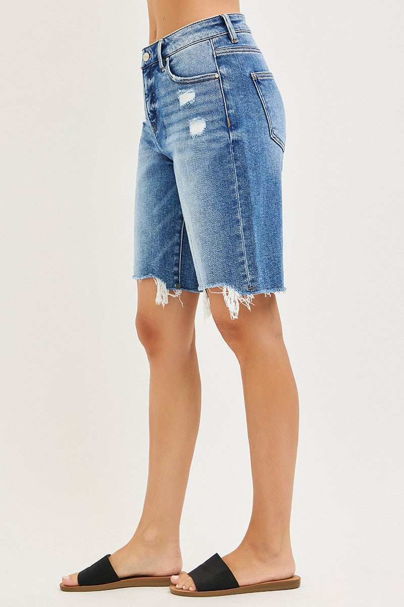 Denim shorts worn by a person on a plain background
