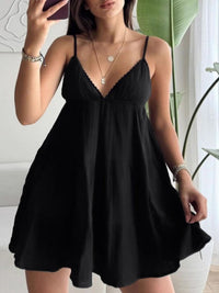 Woman wearing a black dress indoors with a plant in the background