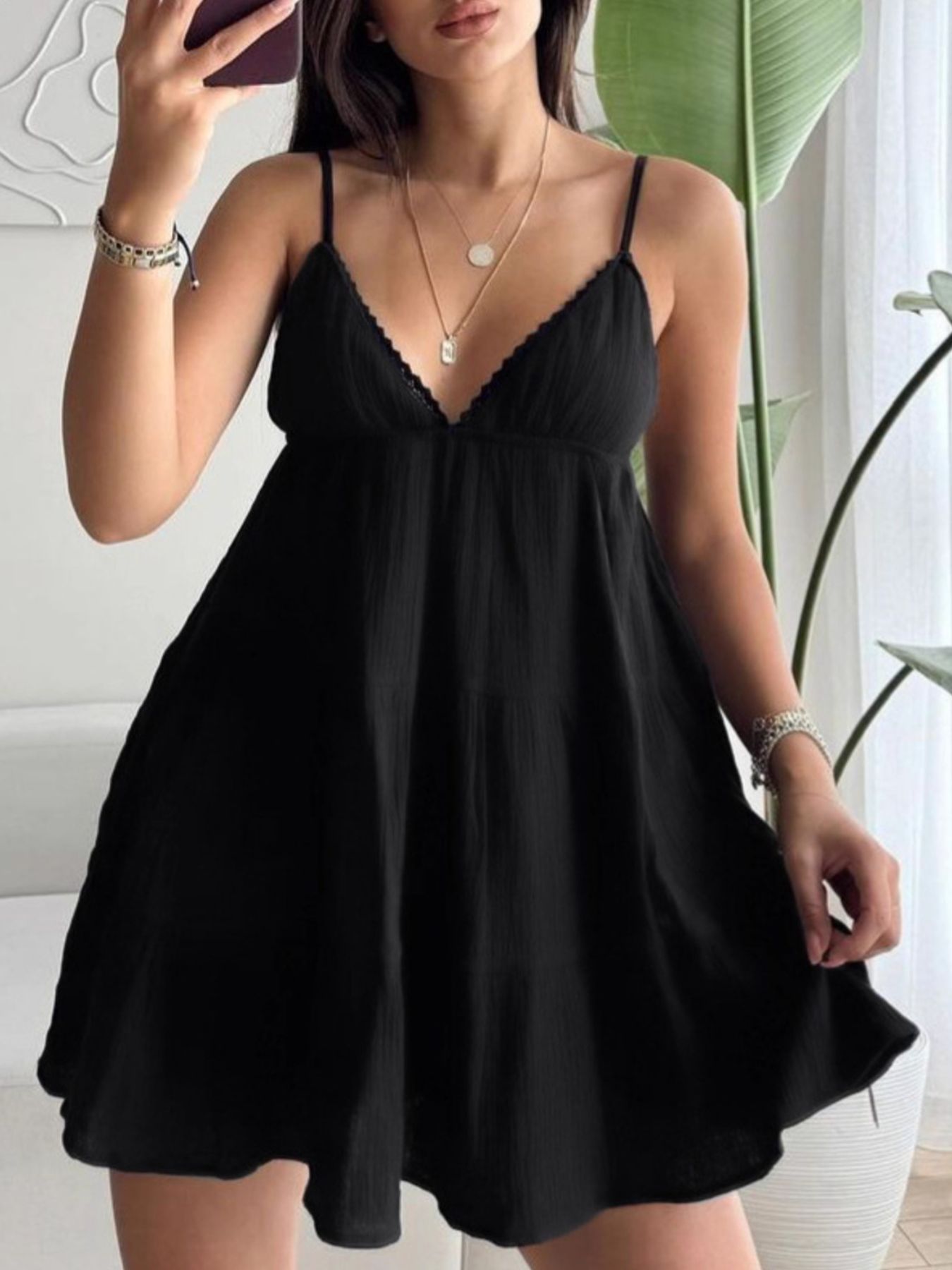 Woman wearing a black dress indoors with a plant in the background