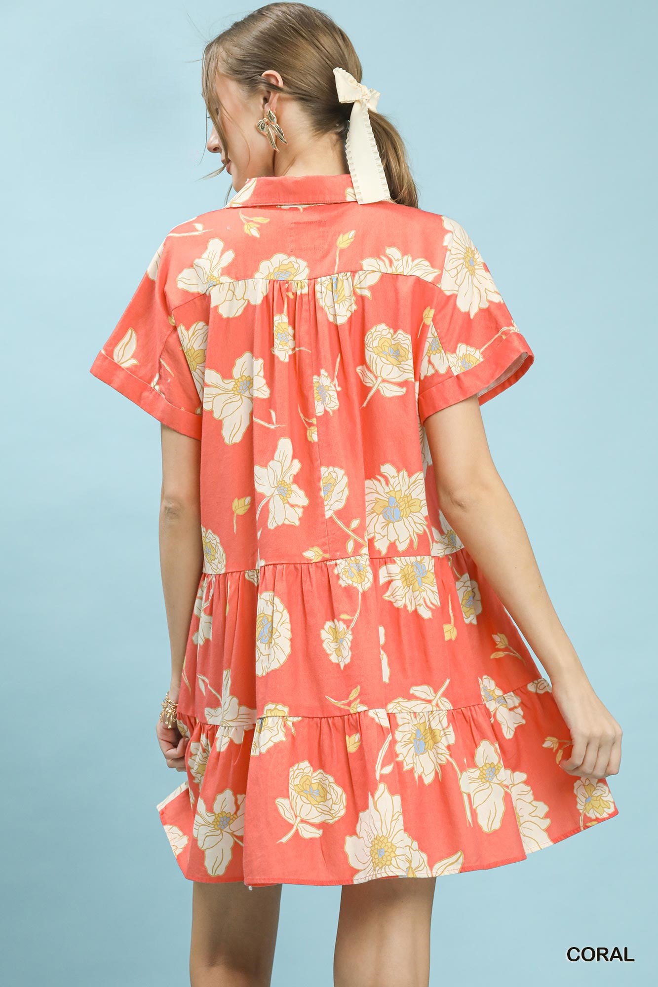 Woman wearing a coral floral dress against a light blue background