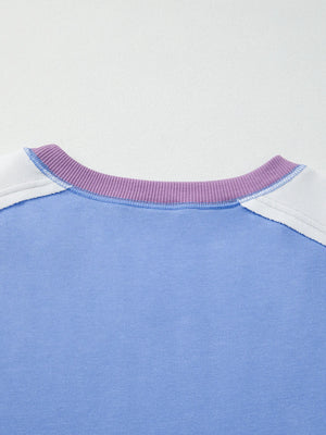 Close-up of a blue shirt with a purple collar and white trim on a light gray background