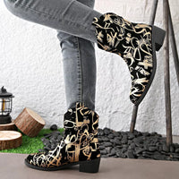 Black and gold patterned boots worn with gray jeans against a white wall.
