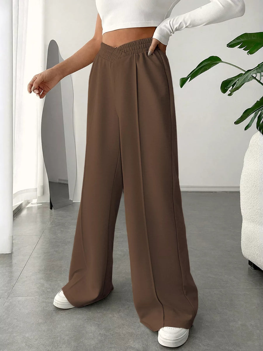 Person wearing brown wide-leg pants and a white top in an indoor setting.
