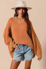 Woman wearing an orange sweater with a wide brimmed hat on a beige background