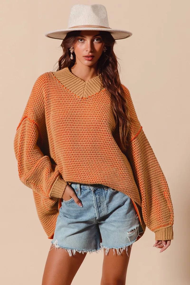 Woman wearing an orange sweater with a wide brimmed hat on a beige background