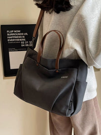 Person holding a gray handbag with brown handles against a neutral background