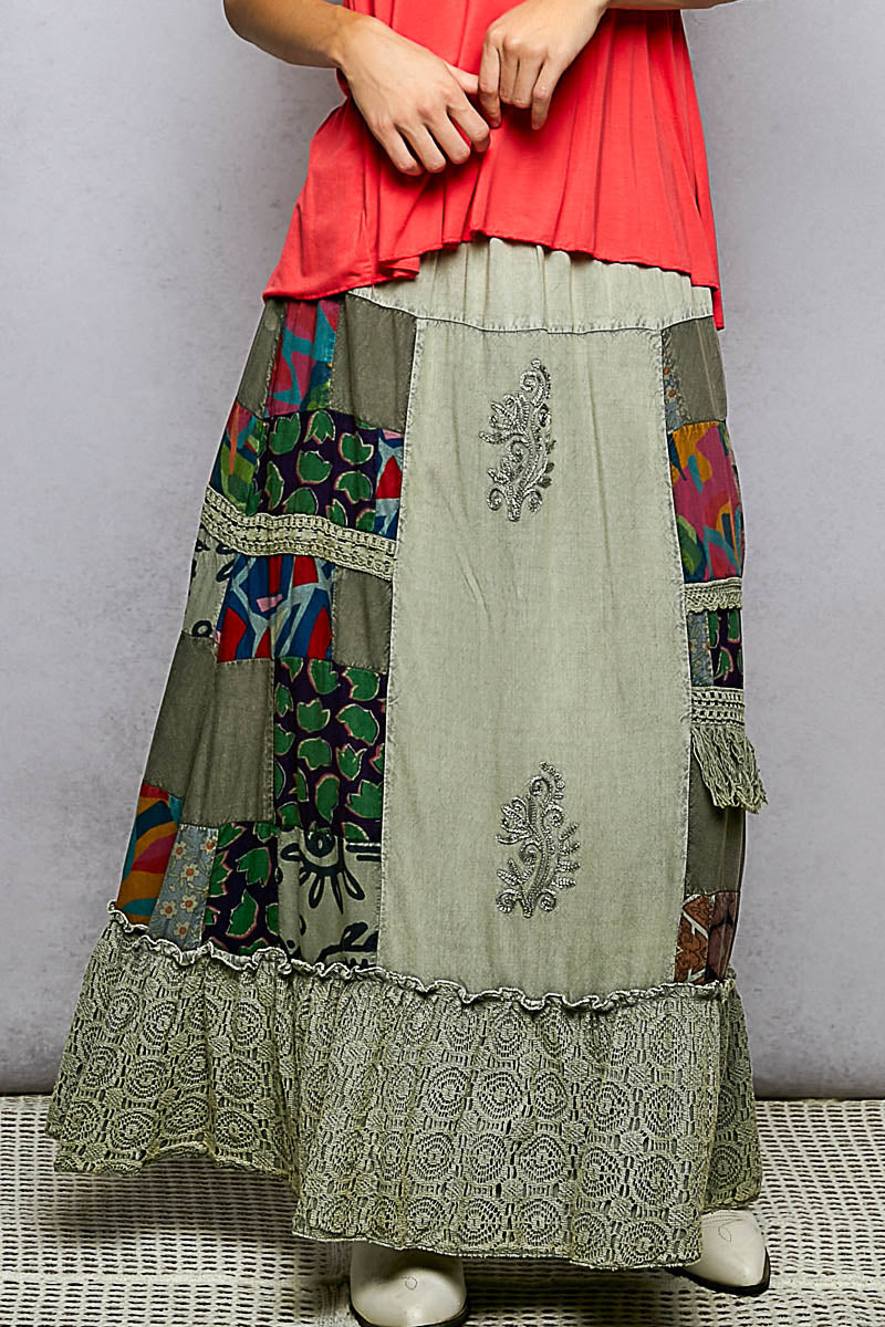 Person wearing a colorful patchwork skirt with intricate patterns on a plain background