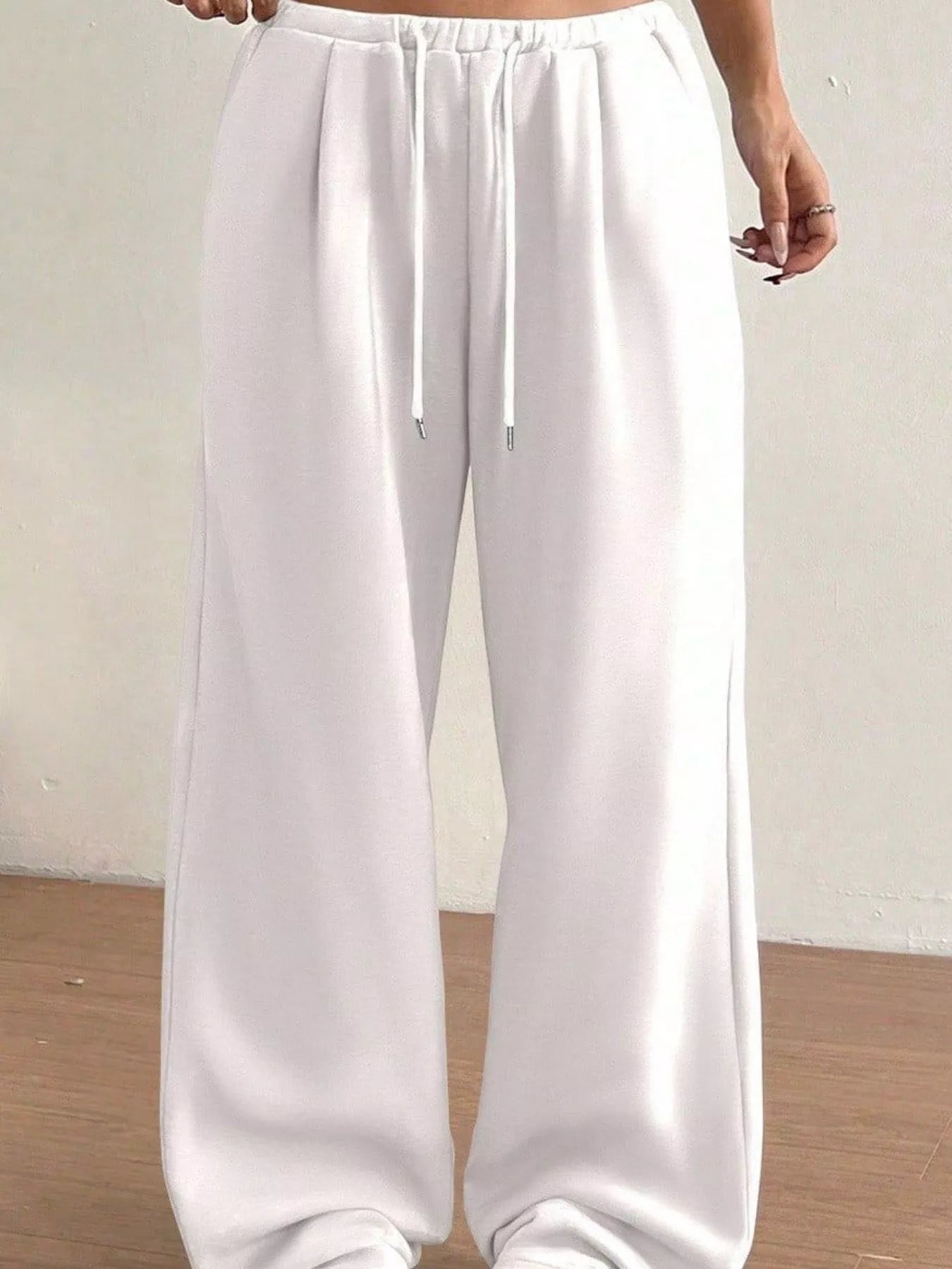 White wide-leg pants with a drawstring waist on a plain background