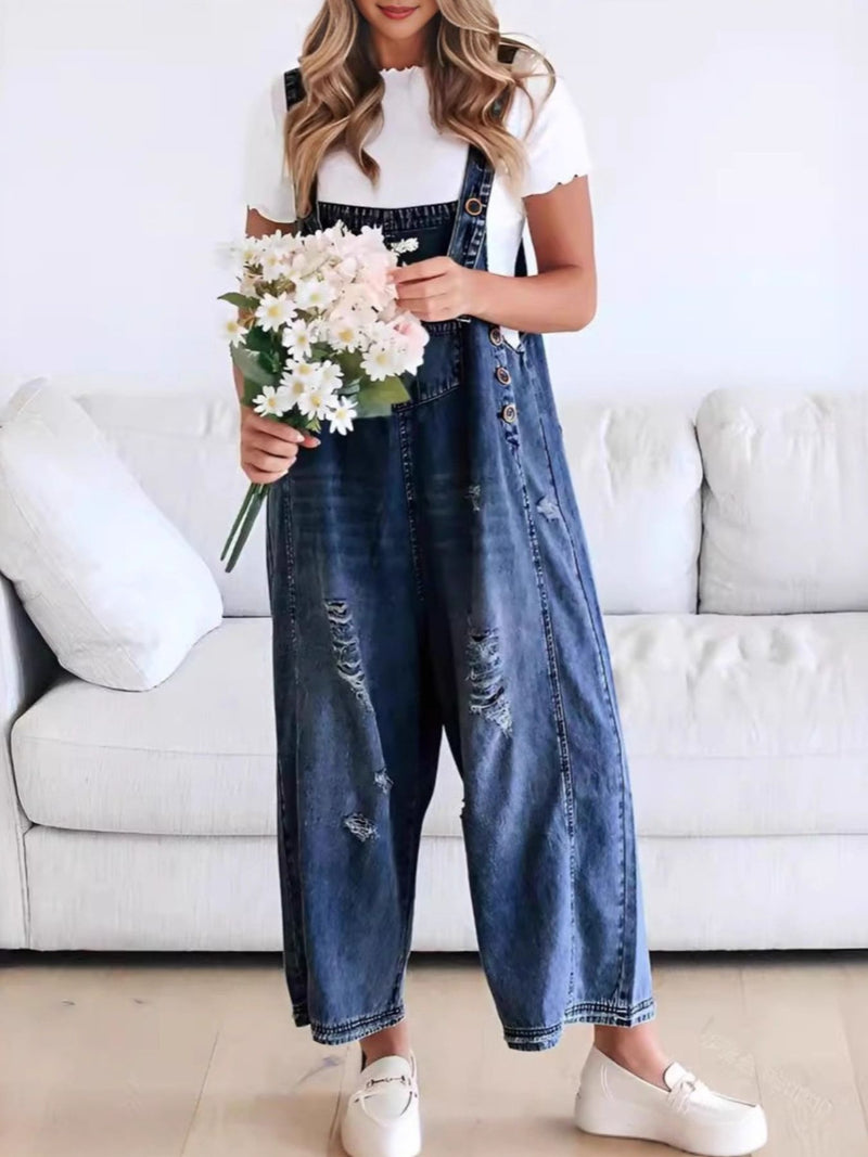 Person wearing denim overalls holding flowers in a living room setting