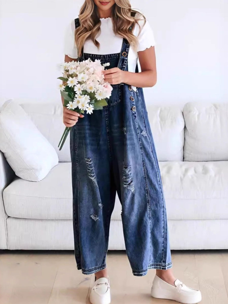 Person wearing denim overalls holding flowers in a living room setting