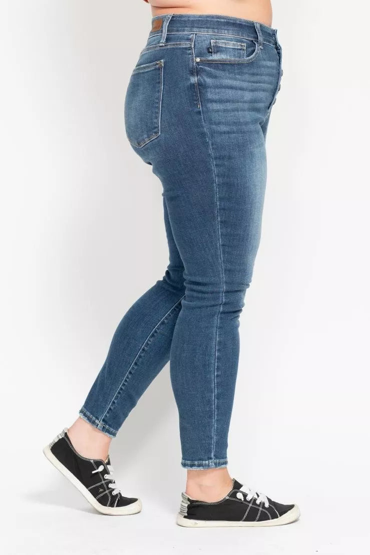 Person wearing blue jeans and black sneakers on a white background
