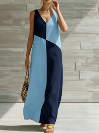 Woman wearing a blue and navy color-blocked dress against a stone wall.