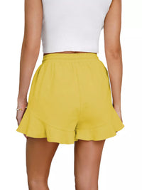 Yellow shorts worn by a person on a white background