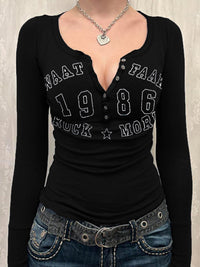 Black long-sleeve top with text and denim jeans on a neutral background