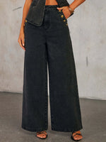 Person wearing black wide-leg jeans with a gray background
