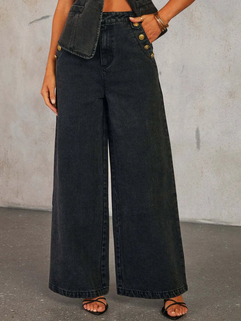Person wearing black wide-leg jeans with a gray background