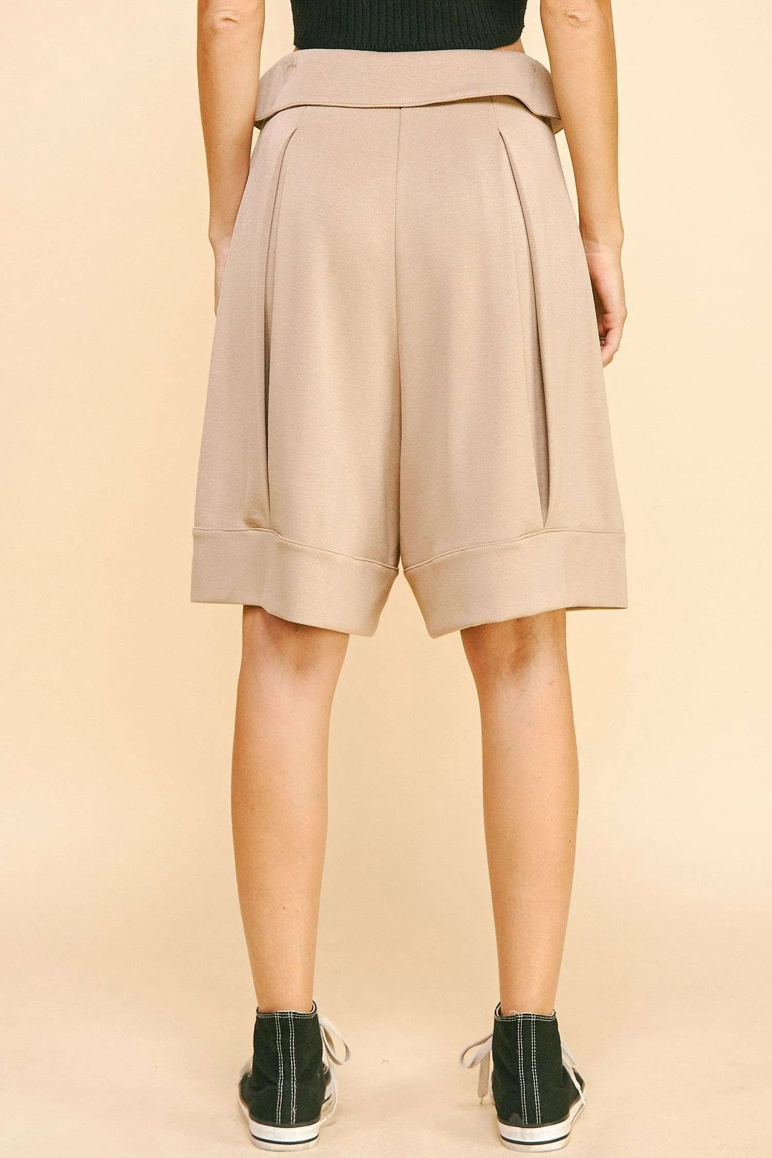 Beige shorts worn by a person on a beige background
