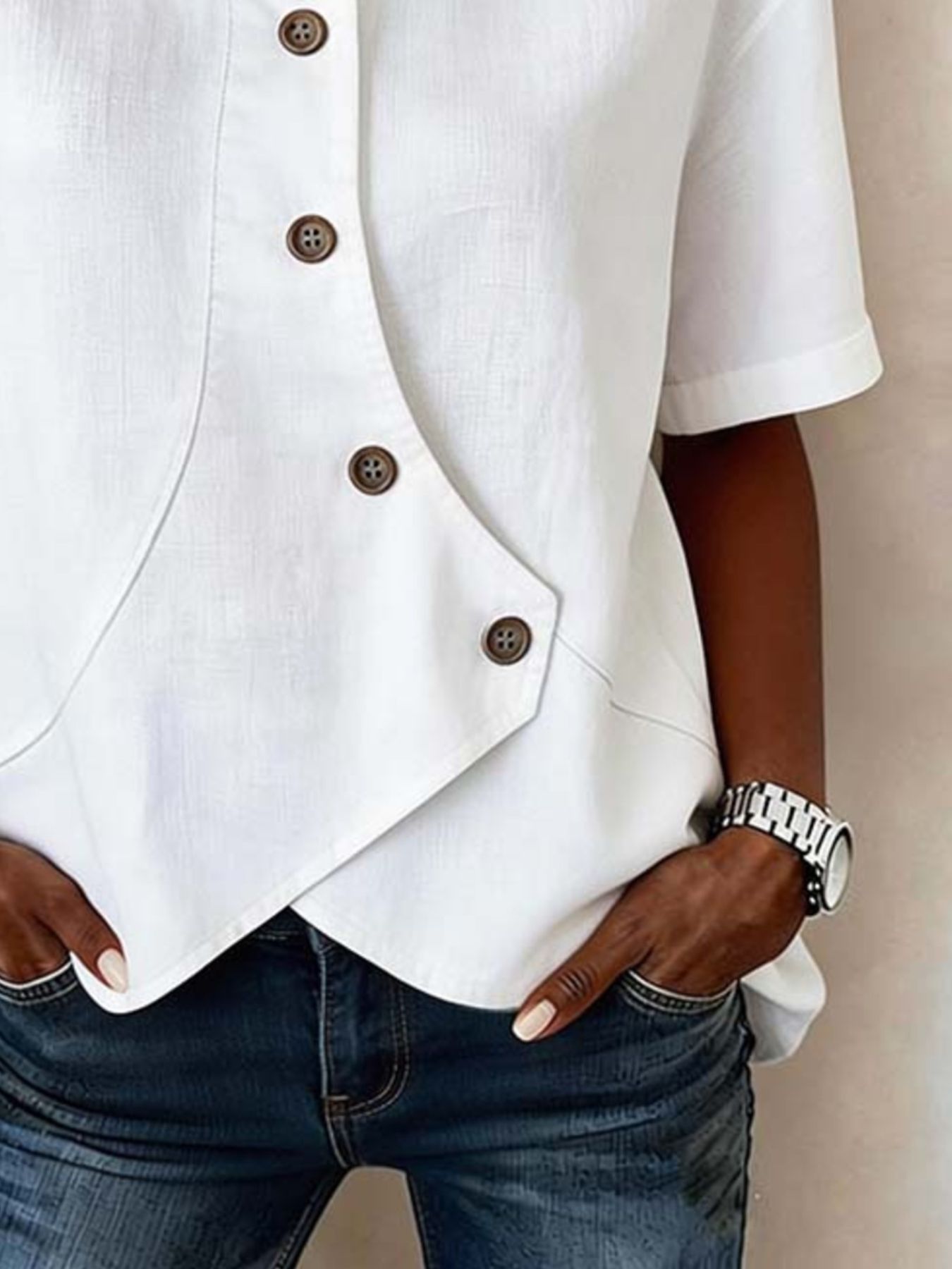 White button-up shirt and blue jeans worn by a person against a neutral background