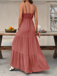 Woman wearing a long rust-colored dress standing in front of a wooden table with fruits.