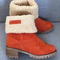 Orange winter boots with white fur lining on a gray background