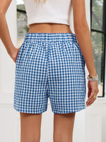 Person wearing blue and white checkered shorts with a blurred background