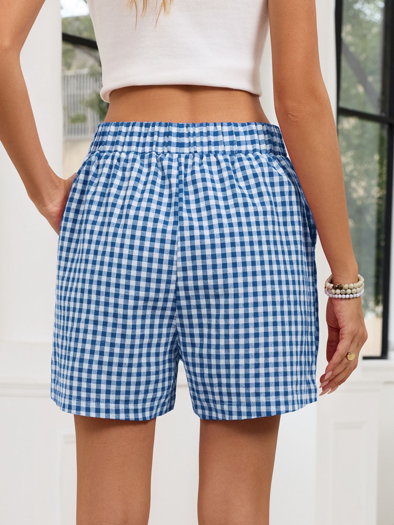 Person wearing blue and white checkered shorts with a blurred background