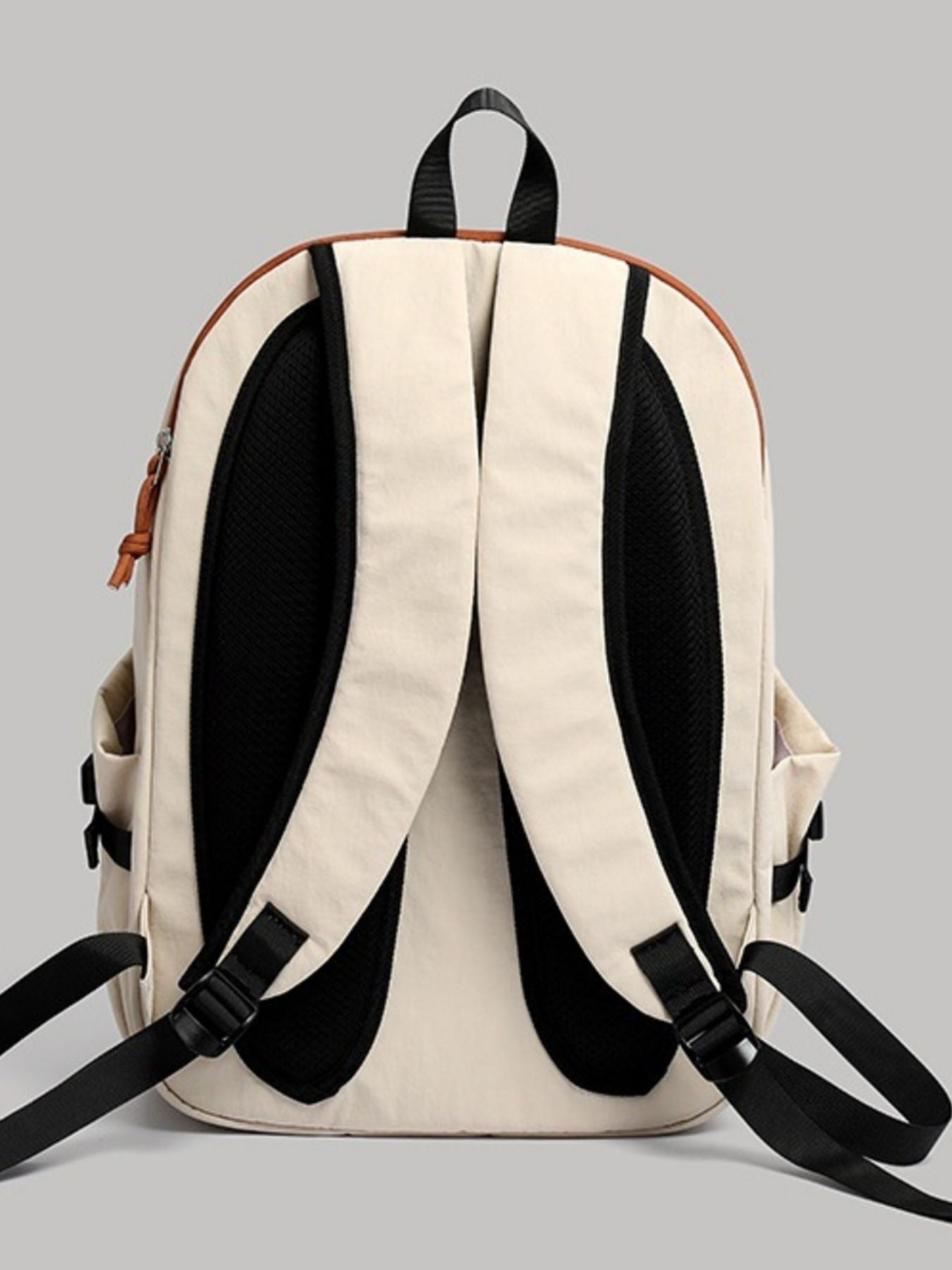 Beige backpack with black straps on a gray background