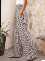 Person wearing black and white checkered pants standing against a stone wall.