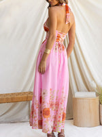 Woman wearing a pink floral dress against a white curtain background