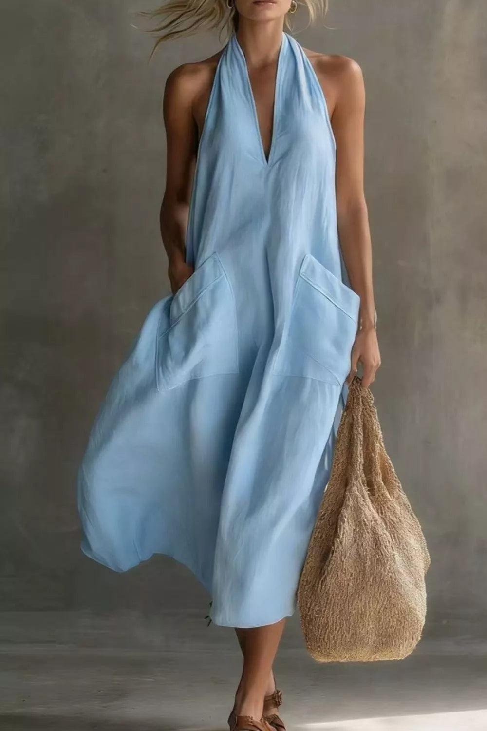 Woman wearing a light blue dress holding a textured bag against a neutral background