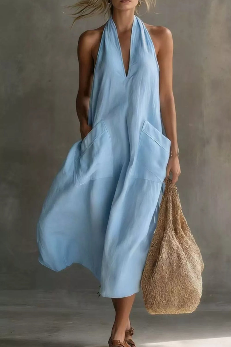 Woman wearing a light blue dress holding a textured bag against a neutral background