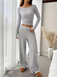 Person wearing a gray ribbed knit outfit in a room with white curtains and decor.