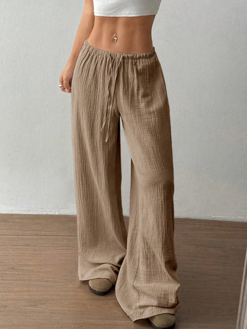 Person wearing beige wide-leg pants against a plain background