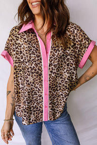 Woman wearing a leopard print shirt with pink trim and blue jeans on a white background