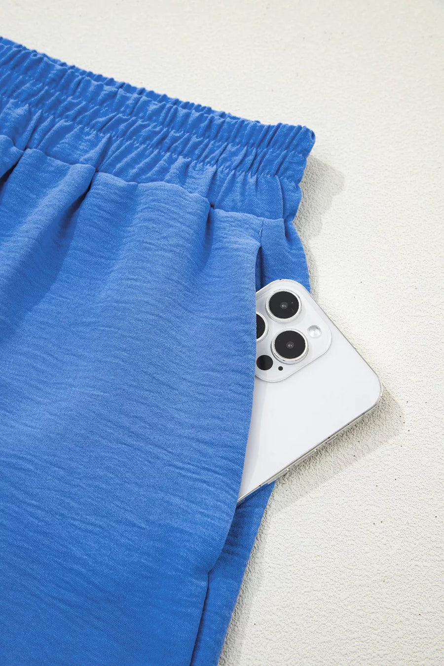 Blue shorts with a white device featuring camera lenses on a light gray background