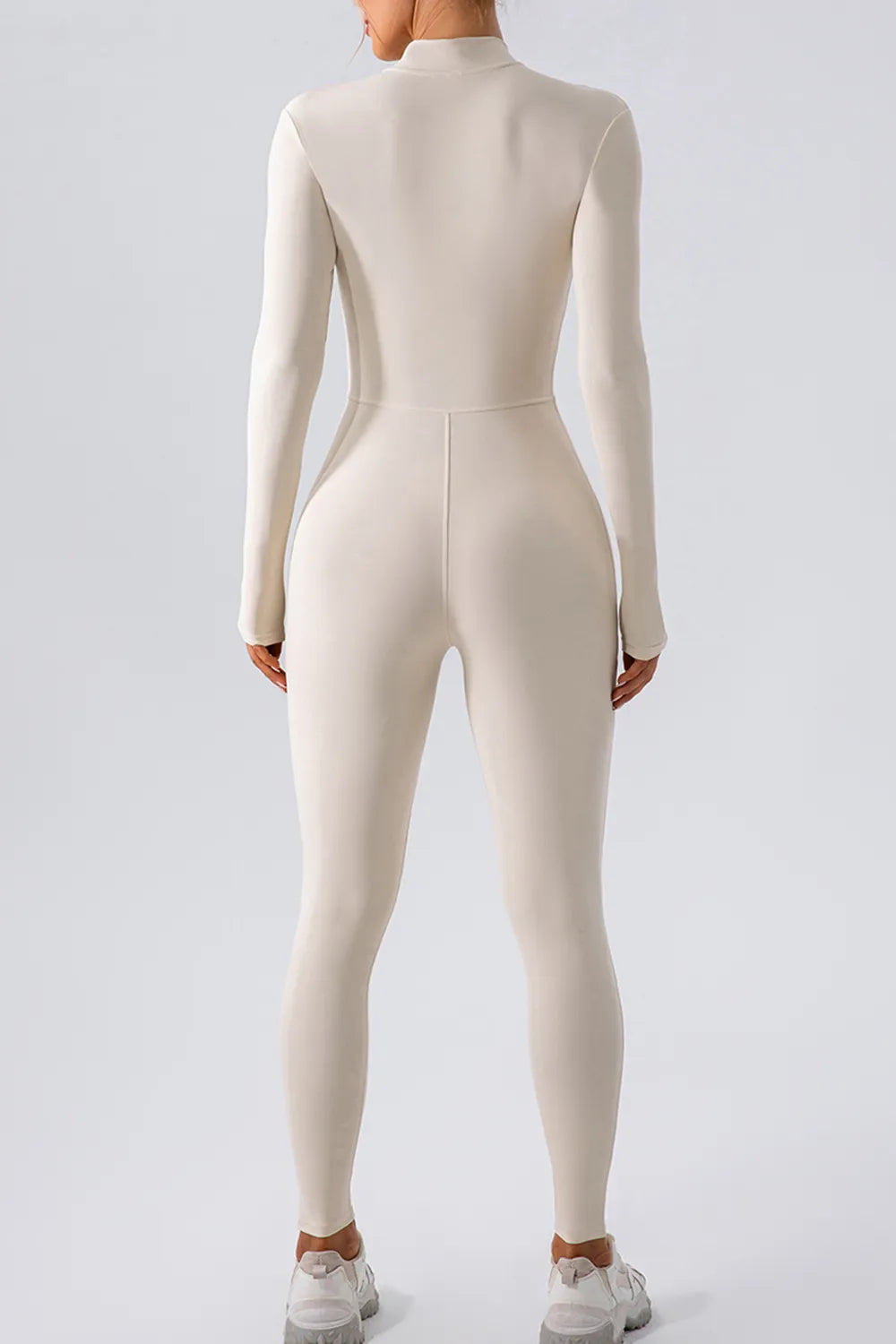 Person wearing a beige bodysuit on a white background