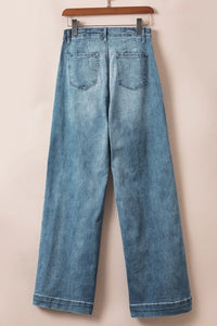 Blue jeans hanging on a wooden hanger against a beige background