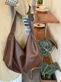 Brown leather bag hanging on a chair with a cafe setting in the background
