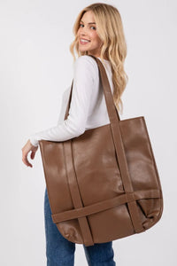 Woman carrying a brown leather tote bag on a white background