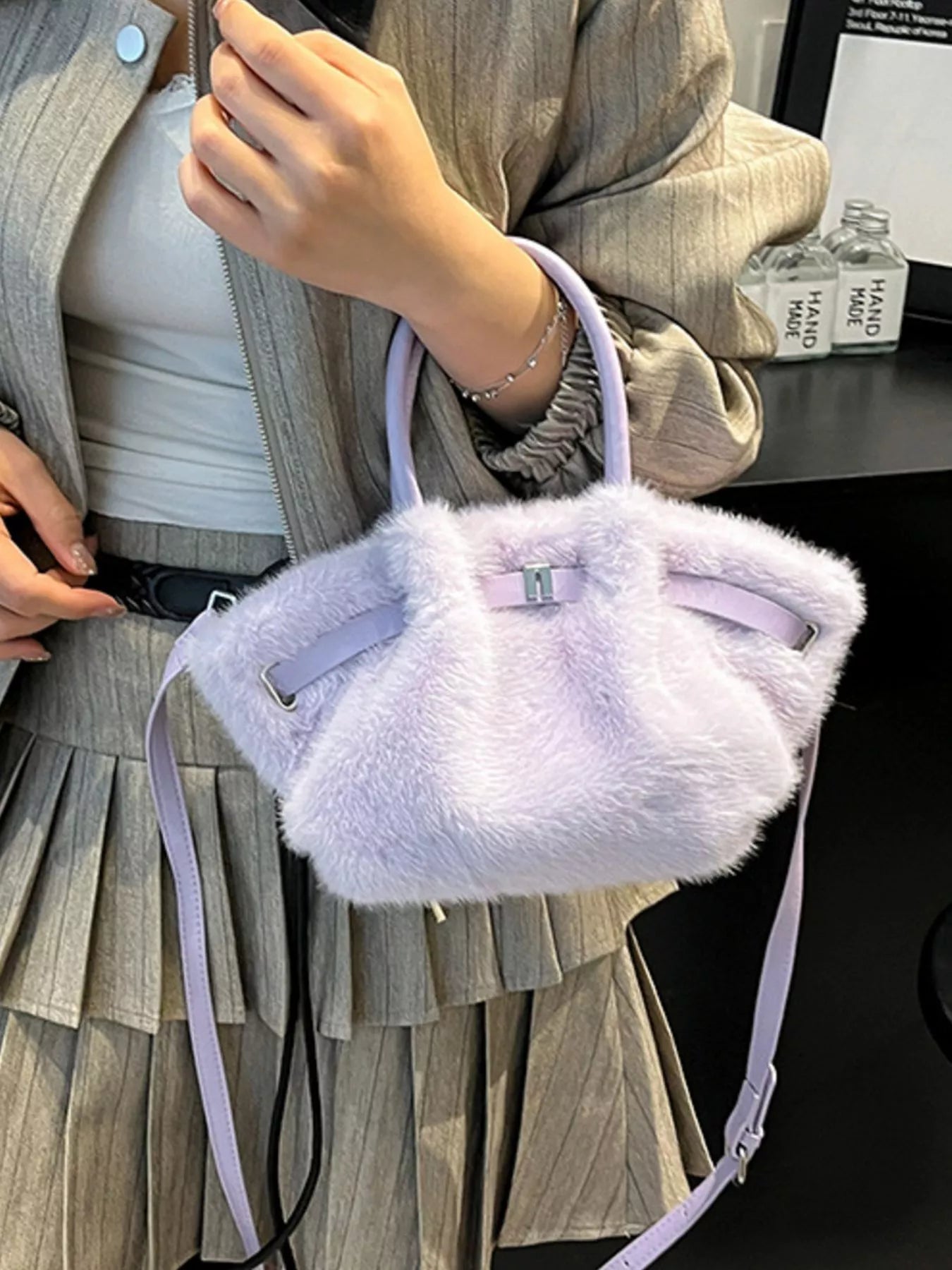 Person holding a fluffy purple handbag with a blurred background