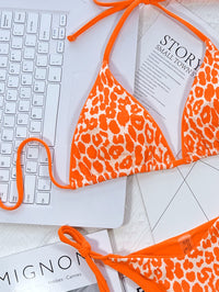 Orange leopard print bikini top on a keyboard with 'Mignon' and 'Story' books in the background.