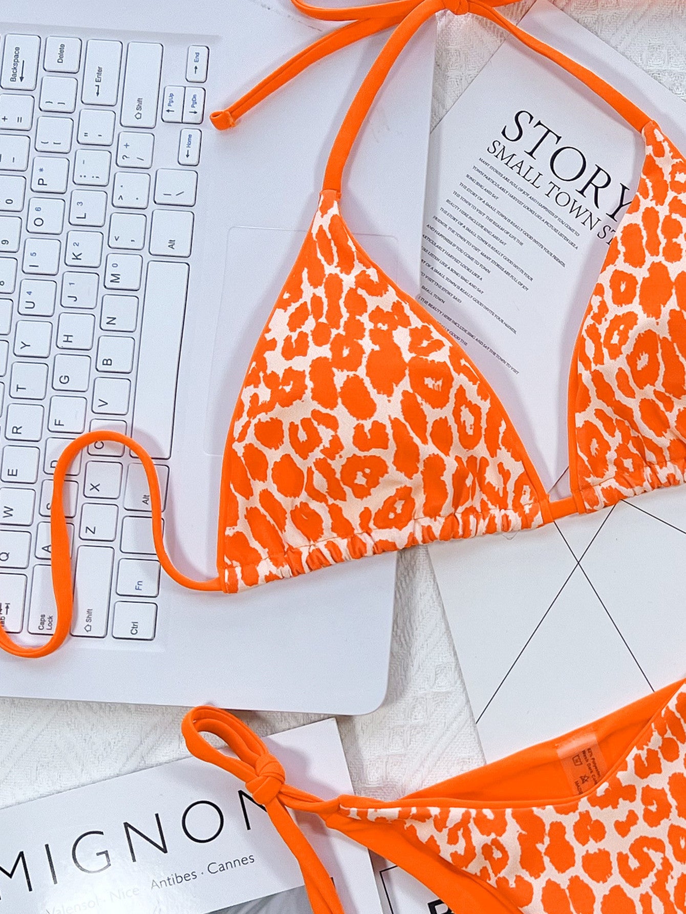 Orange leopard print bikini top on a keyboard with 'Mignon' and 'Story' books in the background.
