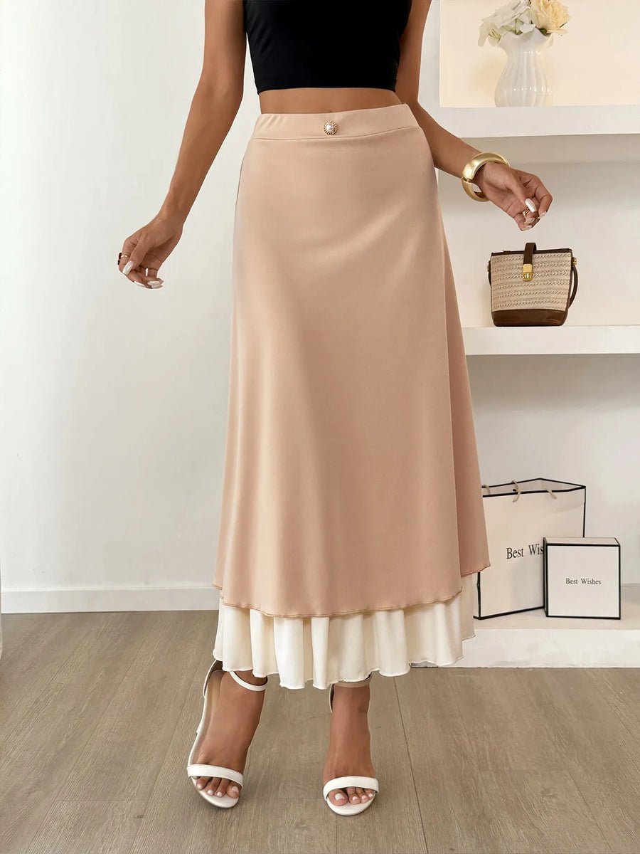 Woman wearing a beige skirt with a white bottom section, standing indoors.