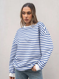 Woman wearing a blue and white striped sweater against a plain background